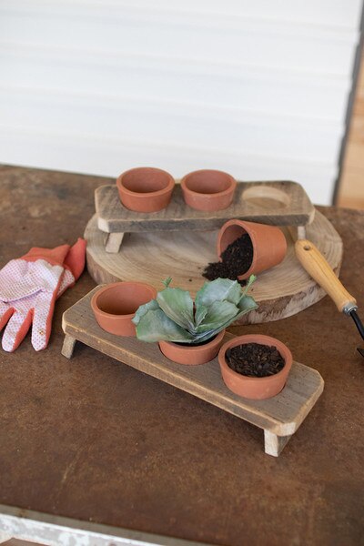 three terracotta flower pots on a recycled wooden base